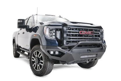 Fab Fours Vengeance front bumper with pre-runner guard on a blue GMC Sierra 2500HD/3500HD, front passenger-side three-quarter view, showing pre-runner hoop, integrated light bar, cube light pods, angular skid plate