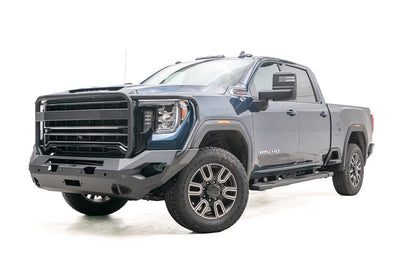 Fab Fours Matrix front bumper with full guard on a blue GMC Sierra 2500HD/3500HD, front driver-side three-quarter view, showing full grille guard, winch-ready center, cube light pods