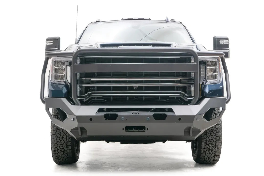 Fab Fours Matrix front bumper with full guard on a blue GMC Sierra 2500HD/3500HD, straight-on front view, showing full grille guard, winch-ready center, cube light pods