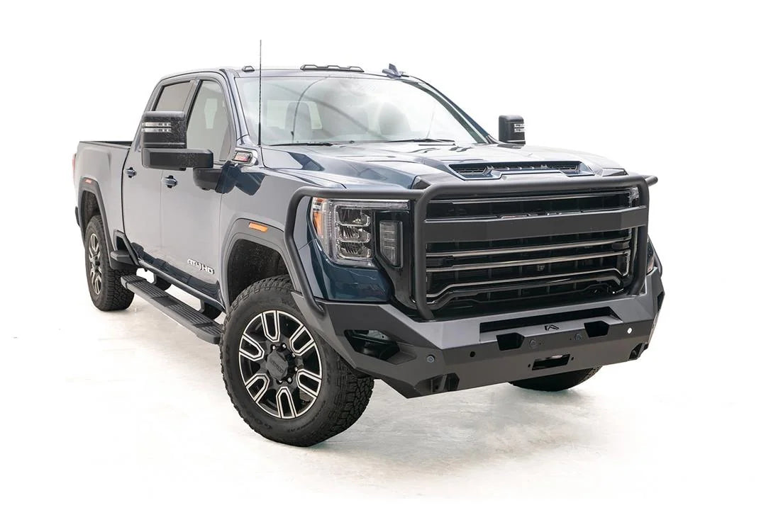 Fab Fours Matrix front bumper with full guard on a blue GMC Sierra 2500HD/3500HD, front passenger-side three-quarter view, showing full grille guard, winch-ready center, cube light pods
