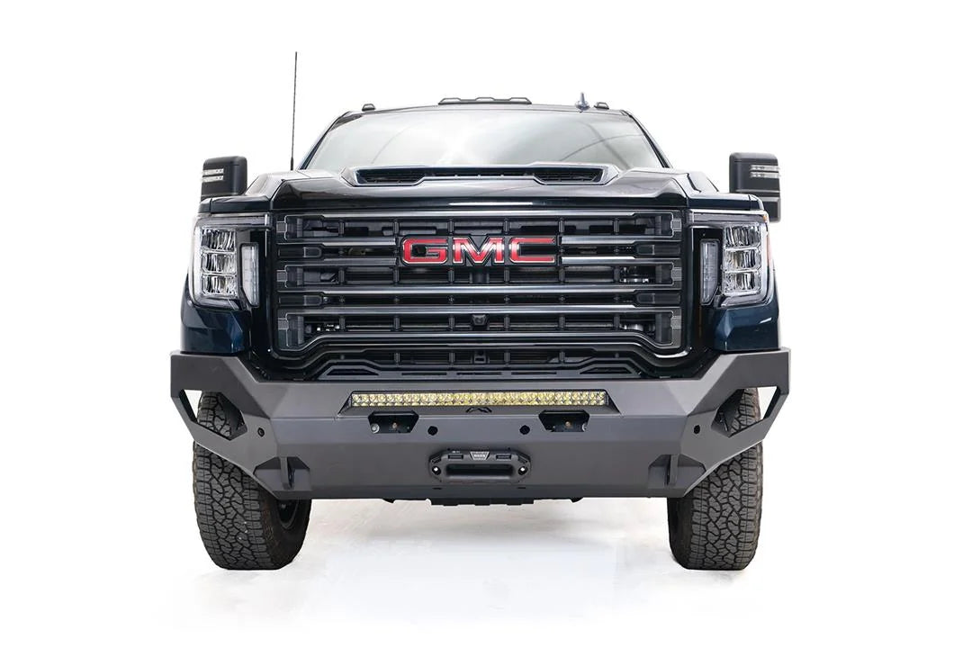 Fab Fours Matrix front bumper on a blue GMC Sierra 2500HD/3500HD, straight-on front view, showing integrated light bar, winch-ready center, cube light pods