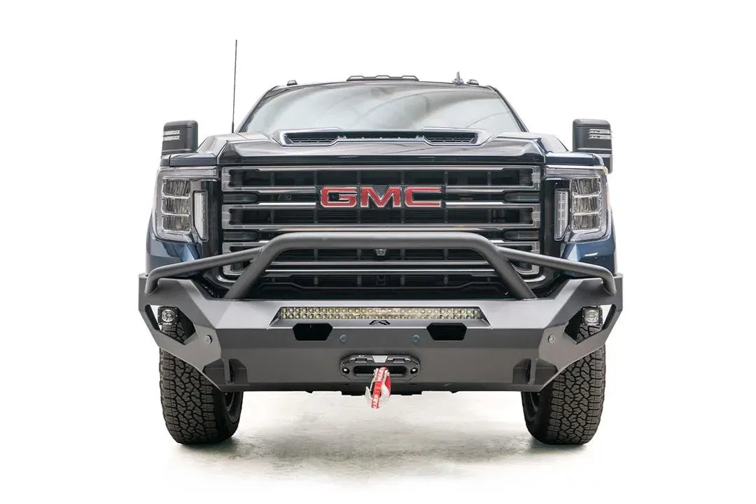 Fab Fours Matrix front bumper with pre-runner guard on a blue GMC Sierra 2500HD/3500HD, straight-on front view, showing pre-runner hoop, integrated light bar, winch-ready center