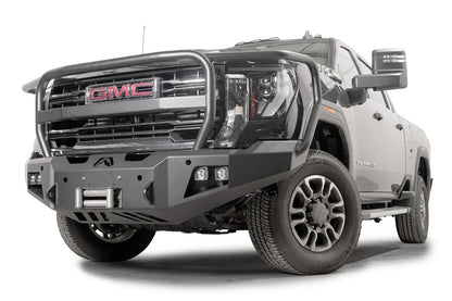 Fab Fours Premium Winch front bumper with full guard on a black GMC Sierra 2500HD/3500HD, front driver-side three-quarter view, showing full guard hoop, winch mount, cube light pods, angled end caps