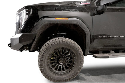 Fab Fours Premium Winch front bumper on a black GMC Sierra 2500HD/3500HD, close-up of the front corner, showing bumper end cap profile, wheel-well clearance