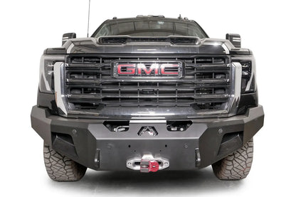 Fab Fours Premium Winch front bumper on a black GMC Sierra 2500HD/3500HD, straight-on front view, showing winch mount, cube light pods, angled end caps