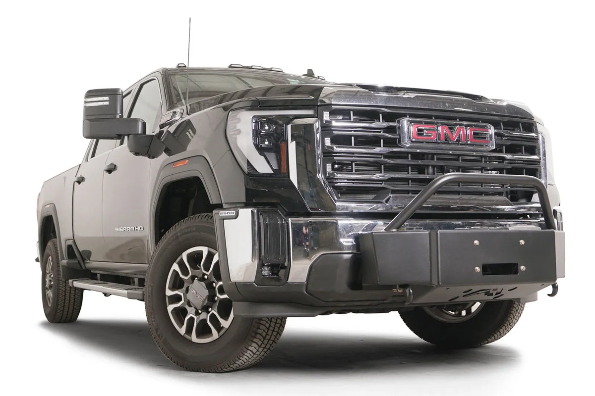 Fab Fours winch mount with pre-runner guard on a black GMC Sierra 2500HD/3500HD, front passenger-side three-quarter view, showing pre-runner hoop, winch plate, factory bumper integration