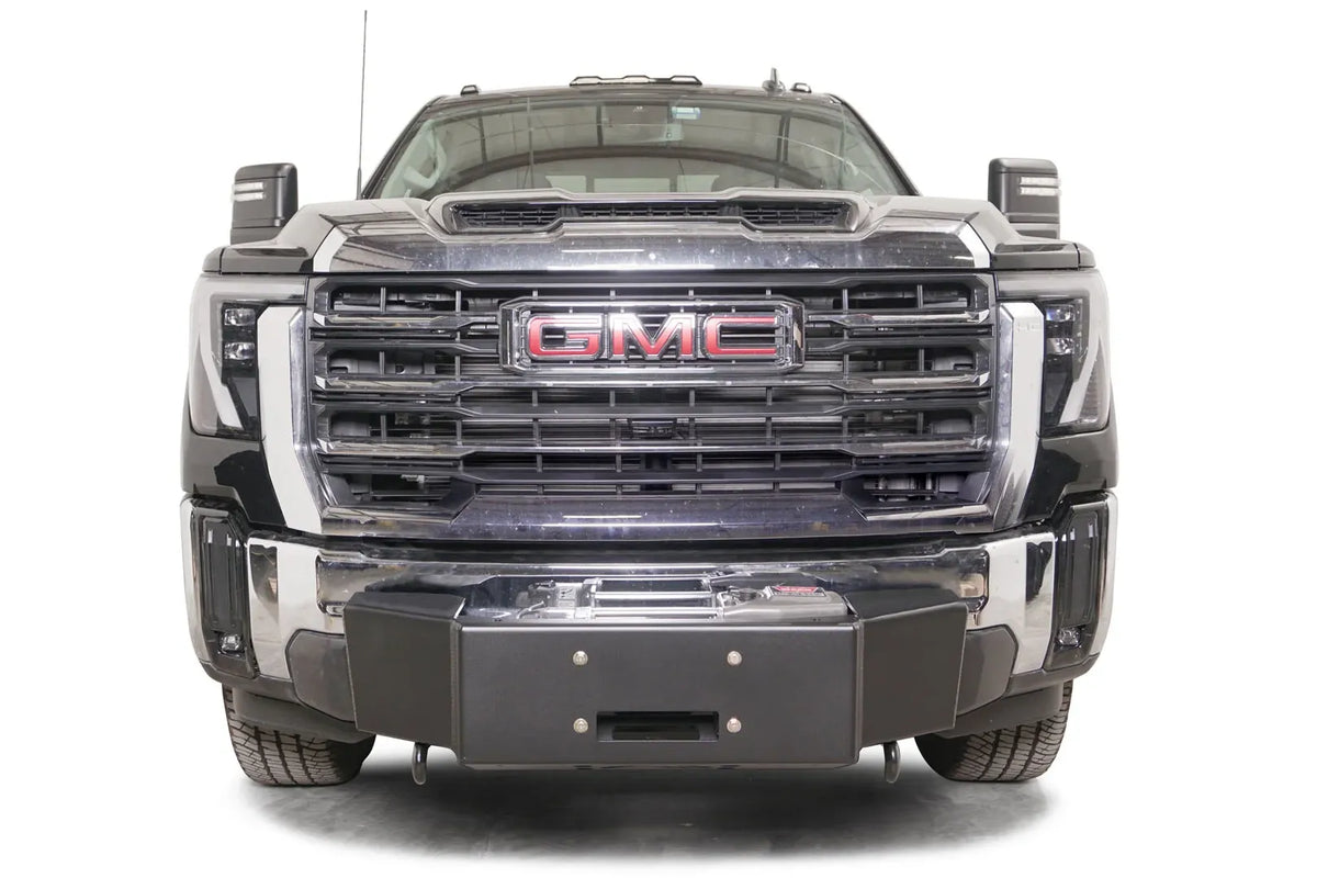 Fab Fours winch mount on a black GMC Sierra 2500HD/3500HD, straight-on front view, showing winch plate, factory bumper integration, center mounting