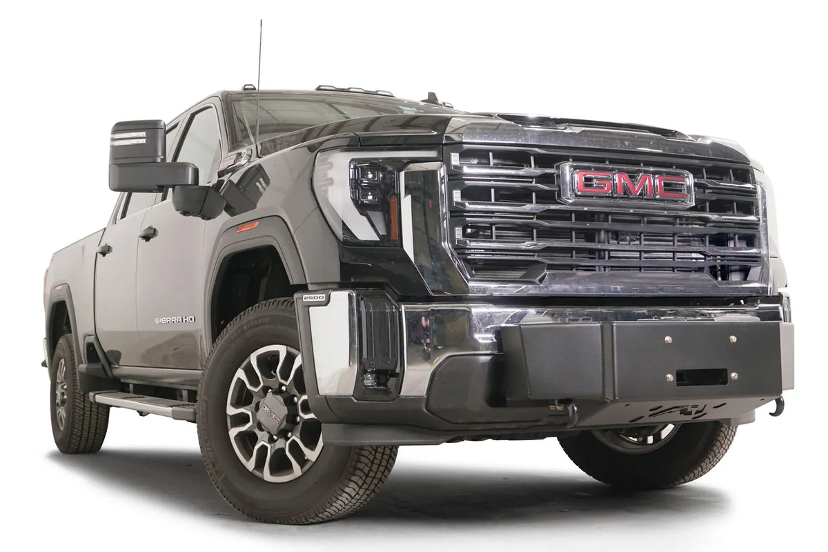 Fab Fours winch mount on a black GMC Sierra 2500HD/3500HD, front passenger-side three-quarter view, showing winch plate, factory bumper integration, center mounting