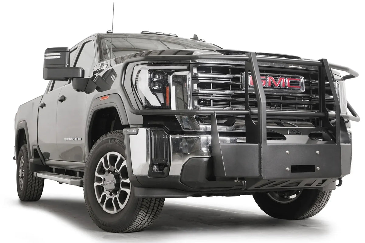 Fab Fours winch mount with full guard on a black GMC Sierra 2500HD/3500HD, front passenger-side three-quarter view, showing full guard uprights, wraparound headlight hoops, winch plate