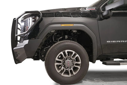 Fab Fours Black Steel Elite front bumper with full guard on a black GMC Sierra 2500HD/3500HD, close-up of the front corner, showing full guard side hoop, bumper end profile, wheel-well clearance