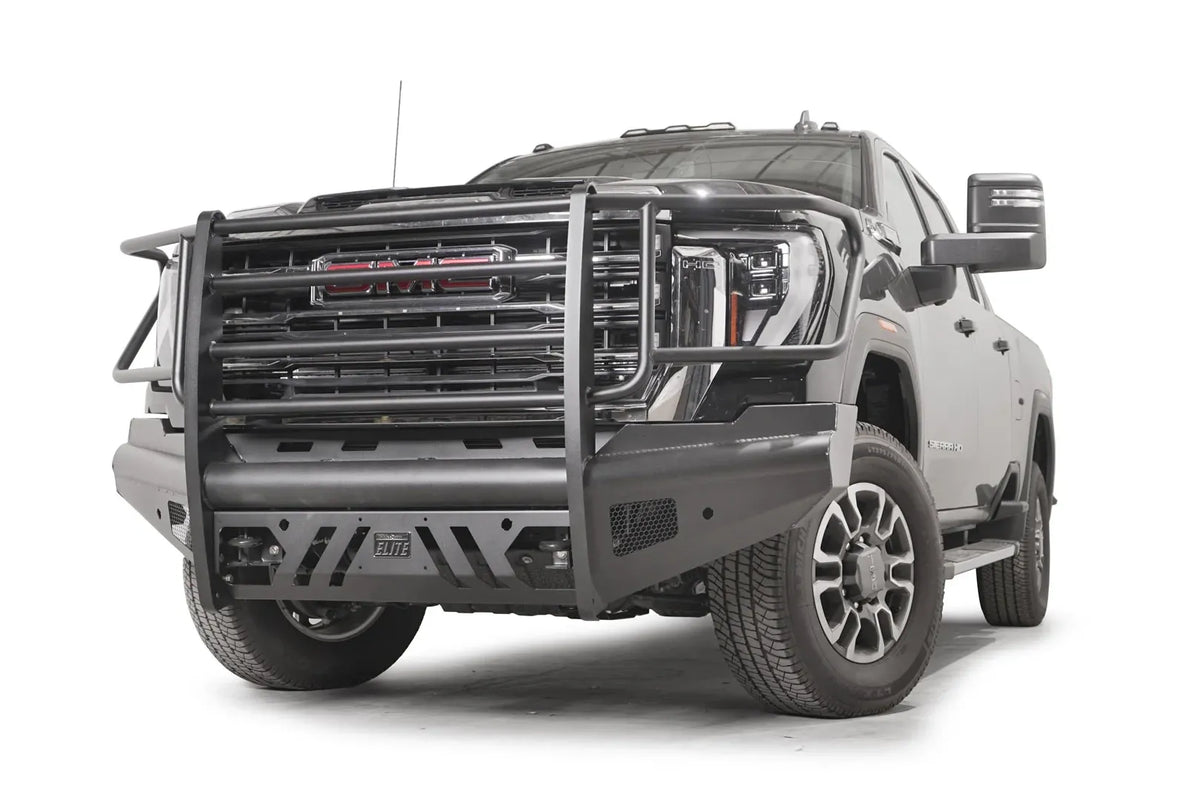 Fab Fours Black Steel Elite front bumper with full guard on a black GMC Sierra 2500HD/3500HD, front driver-side three-quarter view, showing full grille guard, Elite badge, slotted skid plate, mesh end inserts