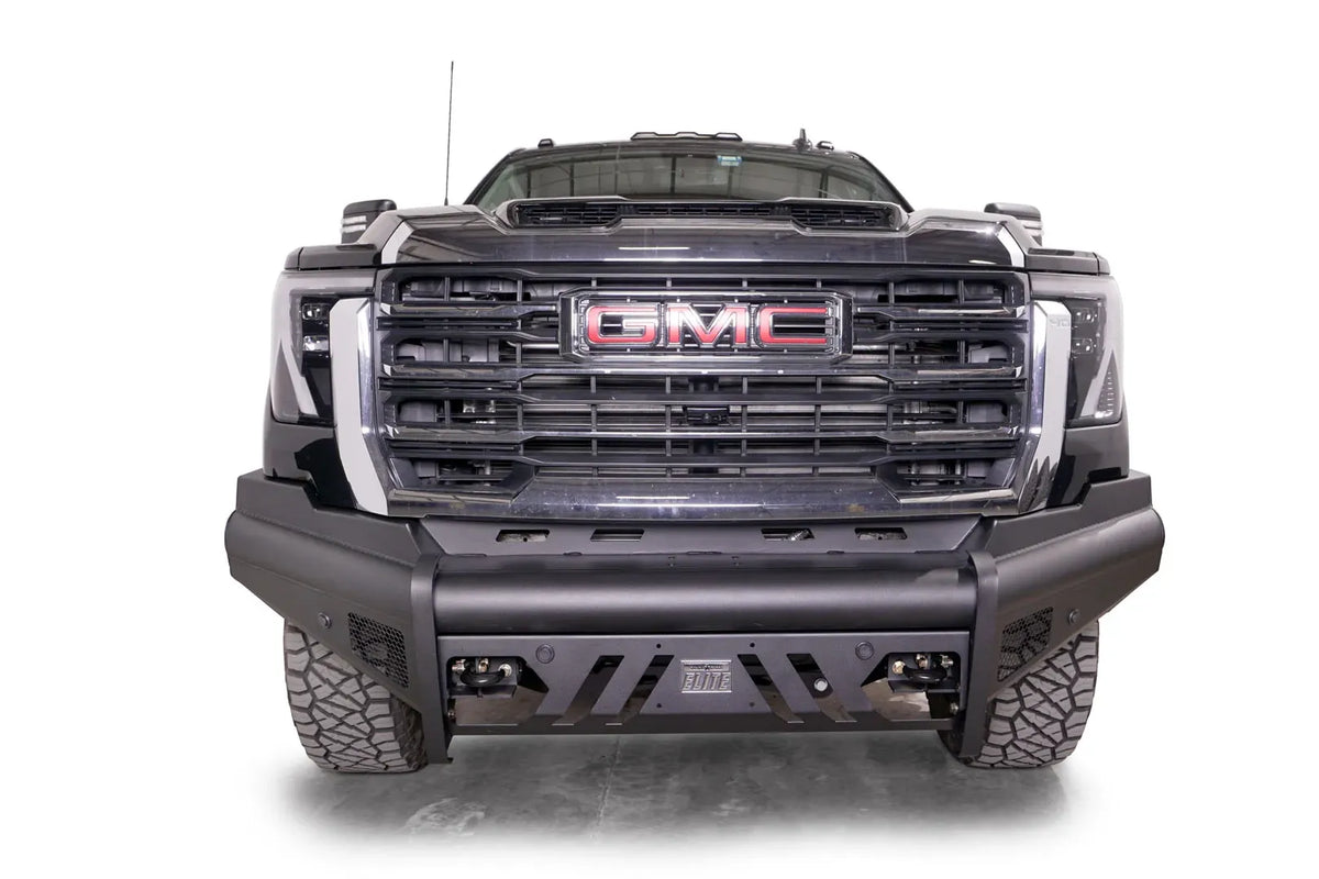 Fab Fours Black Steel Elite front bumper on a black GMC Sierra 2500HD/3500HD, straight-on front view, showing Elite badge, slotted skid plate, mesh end inserts, top tube