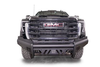 Fab Fours Black Steel Elite front bumper on a black GMC Sierra 2500HD/3500HD, straight-on front view, showing Elite badge, slotted skid plate, mesh end inserts, top tube