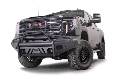 Fab Fours Black Steel Elite front bumper with pre-runner guard on a black GMC Sierra 2500HD/3500HD, front driver-side three-quarter view, showing pre-runner hoop, Elite badge, slotted skid plate, mesh end inserts