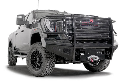 Fab Fours Black Steel front bumper with full guard on a black GMC Sierra 2500HD/3500HD, front passenger-side three-quarter view, showing full grille guard, diamond-plate finish, mesh end inserts, winch