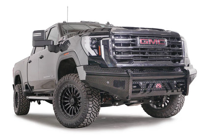 Fab Fours Black Steel front bumper on a black GMC Sierra 2500HD/3500HD, front passenger-side three-quarter view, showing diamond-plate finish, top tube, mesh end inserts, Fab Fours badge