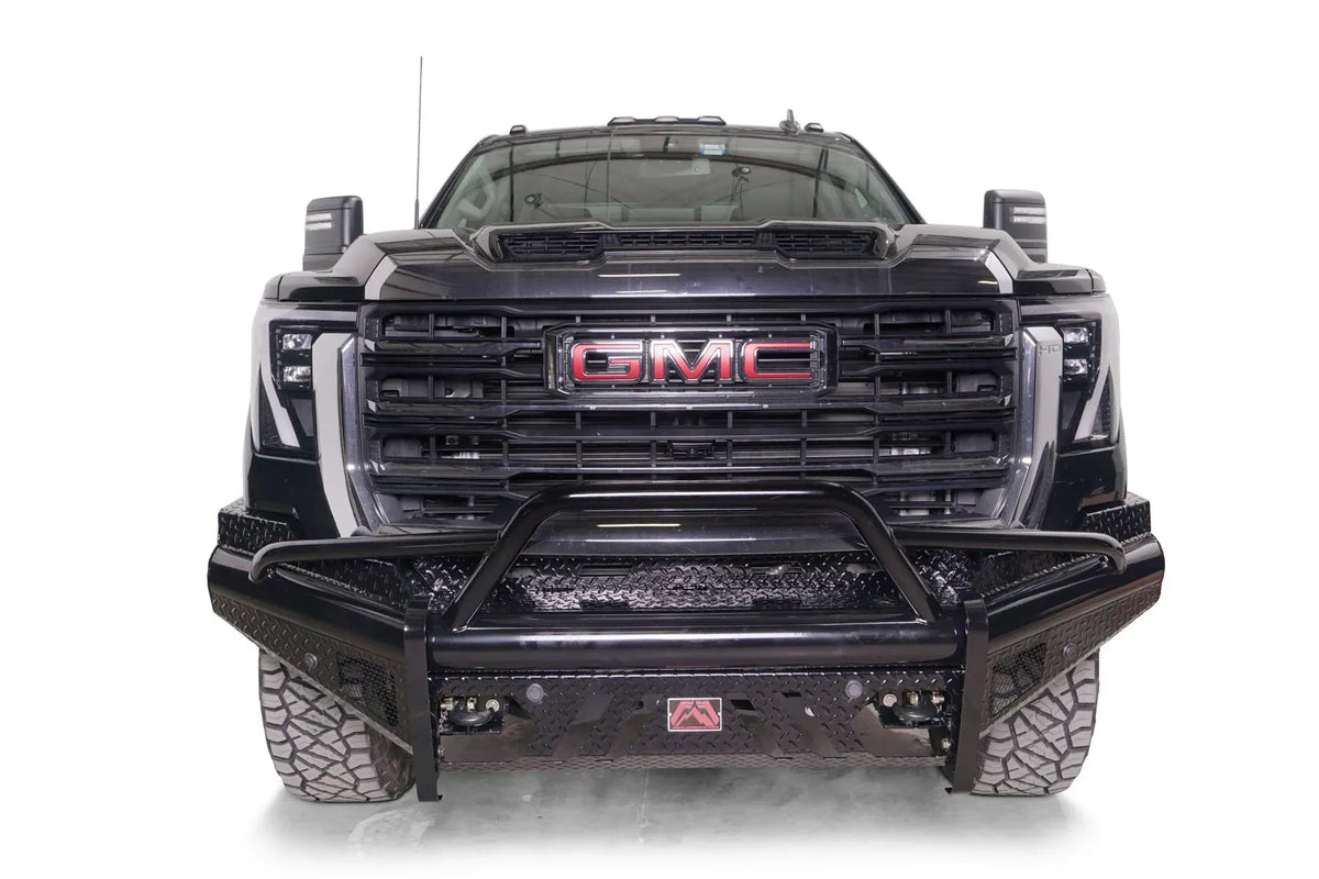 Fab Fours Black Steel front bumper with pre-runner guard on a black GMC Sierra 2500HD/3500HD, straight-on front view, showing pre-runner hoop, diamond-plate finish, mesh end inserts, Fab Fours badge