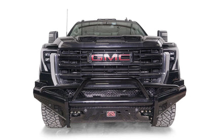 Fab Fours Black Steel front bumper with pre-runner guard on a black GMC Sierra 2500HD/3500HD, straight-on front view, showing pre-runner hoop, diamond-plate finish, mesh end inserts, Fab Fours badge