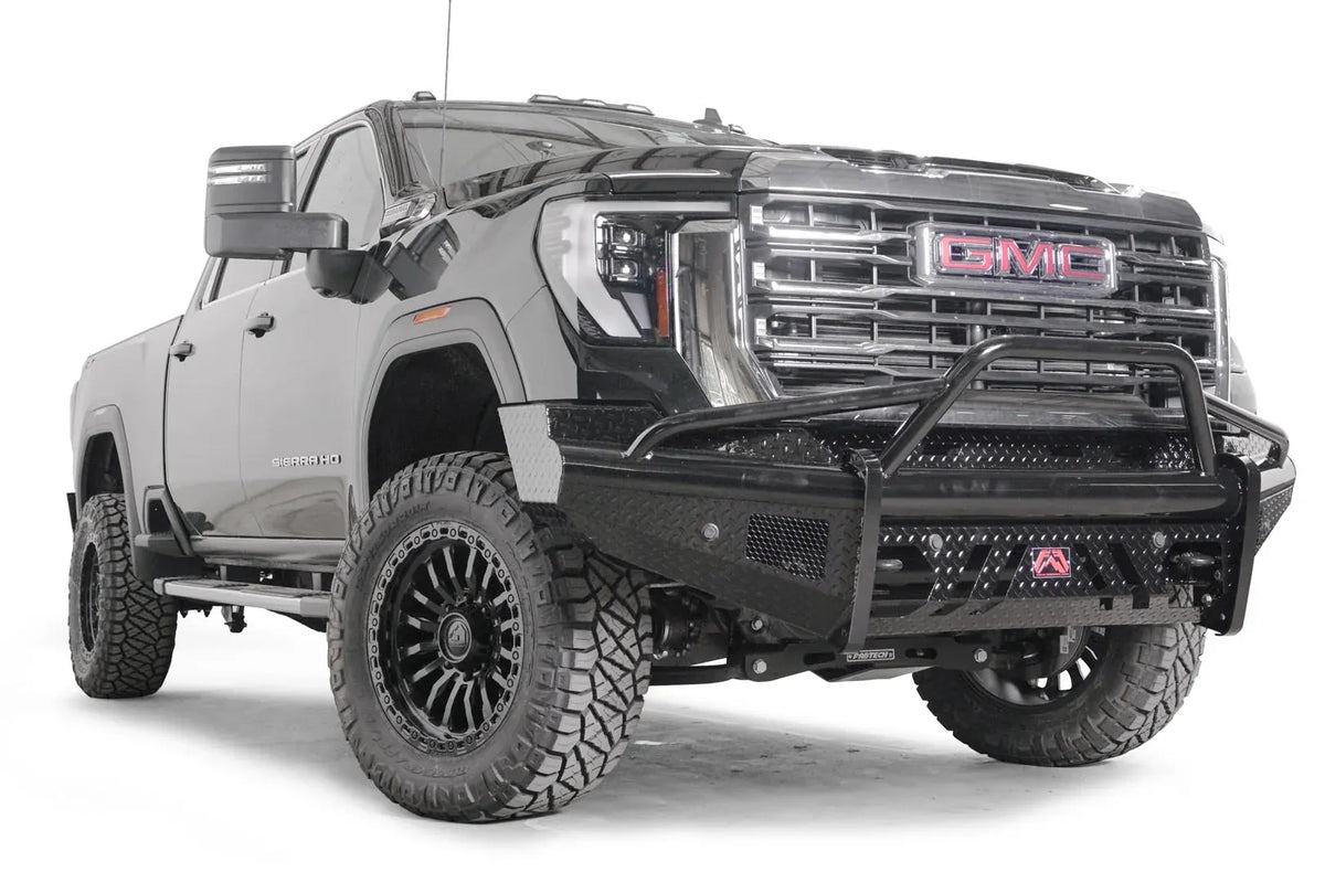 Fab Fours Black Steel front bumper with pre-runner guard on a black GMC Sierra 2500HD/3500HD, front passenger-side three-quarter view, showing pre-runner hoop, diamond-plate finish, mesh end inserts, Fab Fours badge