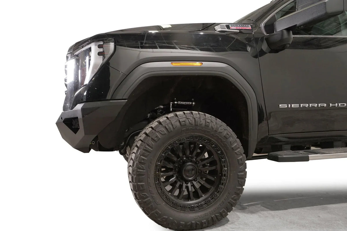 Fab Fours Vengeance front bumper on a black GMC Sierra 2500HD/3500HD, close-up of the front corner, showing angular end cap, bumper profile, wheel-well clearance