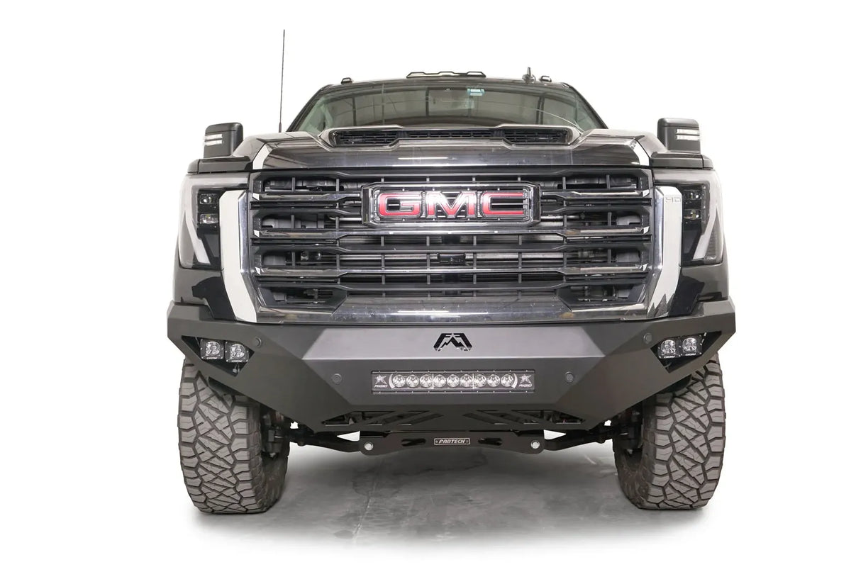 Fab Fours Vengeance front bumper on a black GMC Sierra 2500HD/3500HD, straight-on front view, showing integrated light bar, cube light pods, angular skid plate