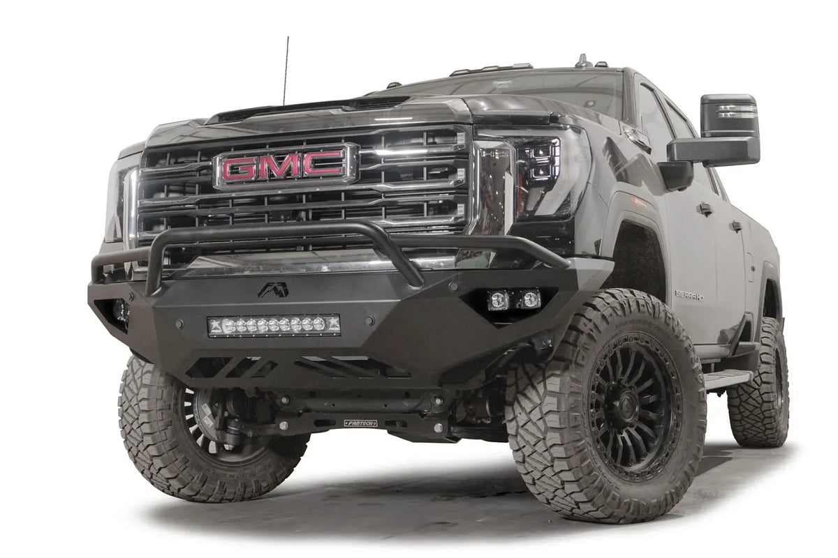 Fab Fours Vengeance front bumper with pre-runner guard on a black GMC Sierra 2500HD/3500HD, front driver-side three-quarter view, showing pre-runner hoop, integrated light bar, cube light pods