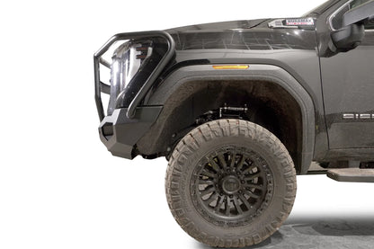 Fab Fours Matrix front bumper with full guard on a dark gray GMC Sierra 2500HD/3500HD, close-up of the front corner, showing full guard side hoop, bumper end cap, wheel-well clearance