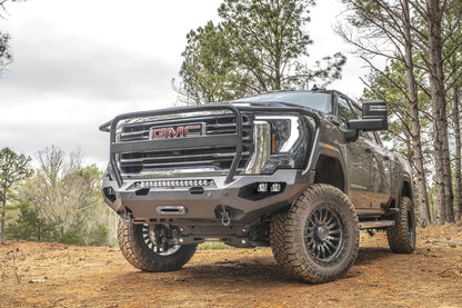 Fab Fours Matrix front bumper with full guard on a dark gray GMC Sierra 2500HD/3500HD, front driver-side three-quarter view outdoors, showing full guard hoop, integrated light bar, cube light pods
