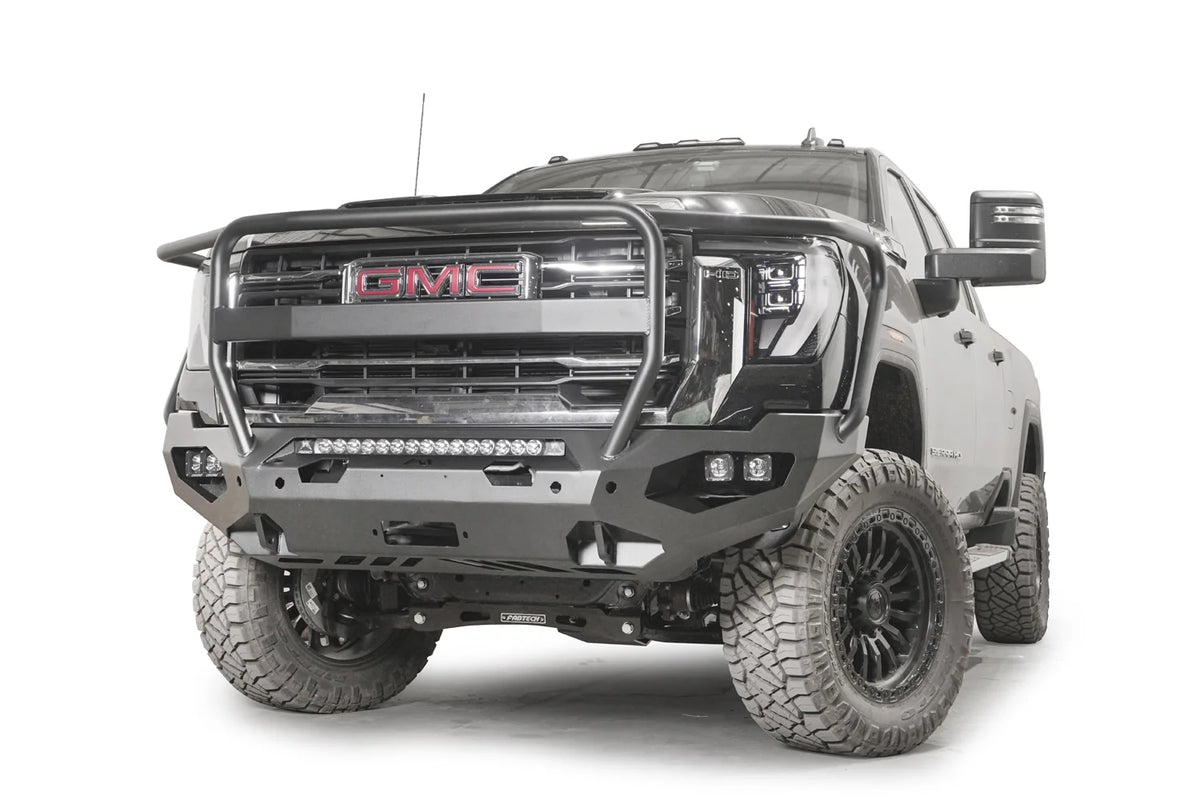 Fab Fours Matrix front bumper with full guard on a dark gray GMC Sierra 2500HD/3500HD, front driver-side three-quarter view, showing full guard hoop, integrated light bar, cube light pods