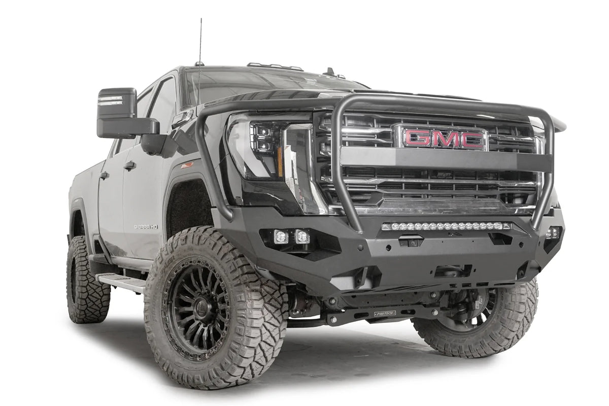 Fab Fours Matrix front bumper with full guard on a dark gray GMC Sierra 2500HD/3500HD, front passenger-side three-quarter view, showing full guard hoop, integrated light bar, cube light pods