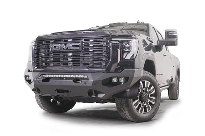 Fab Fours Matrix front bumper on a dark gray GMC Sierra 2500HD/3500HD, front driver-side three-quarter view, showing integrated light bar, cube light pods, winch-ready center