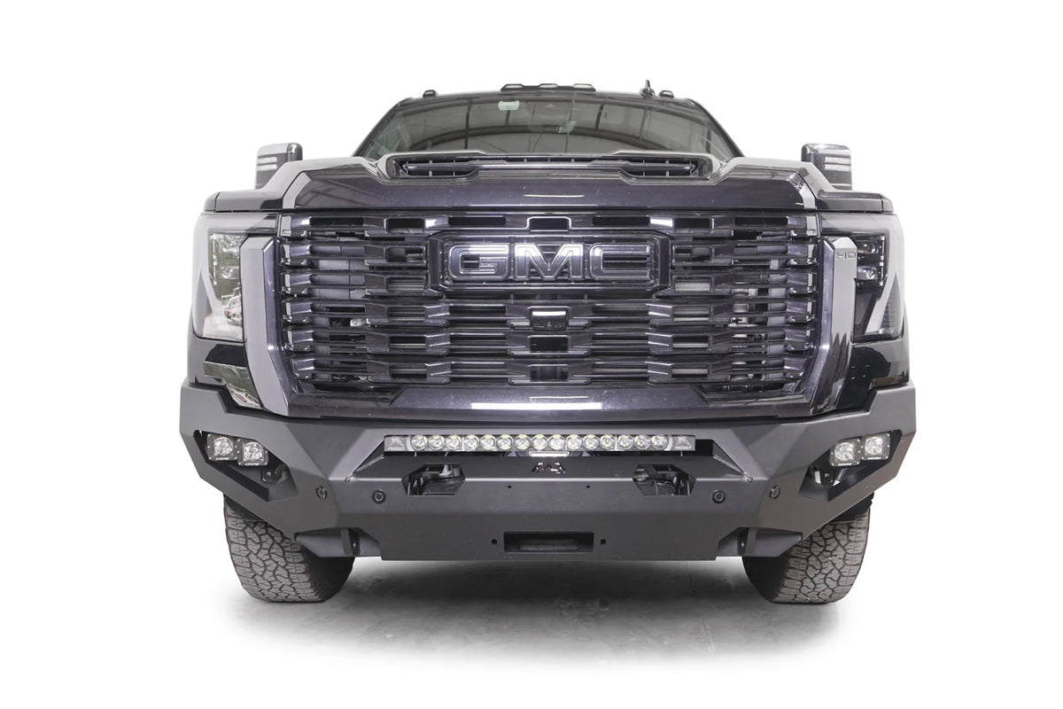 Fab Fours Matrix front bumper on a dark gray GMC Sierra 2500HD/3500HD, straight-on front view, showing integrated light bar, cube light pods, winch-ready center