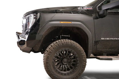 Fab Fours Matrix front bumper with pre-runner guard on a black GMC Sierra 2500HD/3500HD, close-up of the front corner, showing pre-runner hoop, bumper end cap, wheel-well clearance