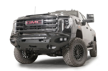 Fab Fours Matrix front bumper with pre-runner guard on a black GMC Sierra 2500HD/3500HD, front driver-side three-quarter view, showing pre-runner hoop, integrated light bar, cube light pods