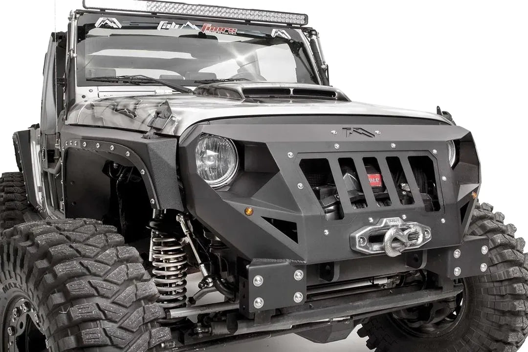 Fab Fours Grumper front bumper in Stubby configuration on a gray Jeep Wrangler JK, close-up of the front corner, showing grille-integrated design, winch and fairlead, bolted plate construction