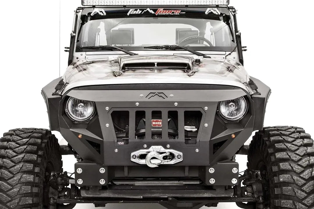 Fab Fours Grumper front bumper in Stubby configuration on a gray Jeep Wrangler JK, close-up of the front corner, showing grille-integrated design, winch and fairlead, bolted plate construction