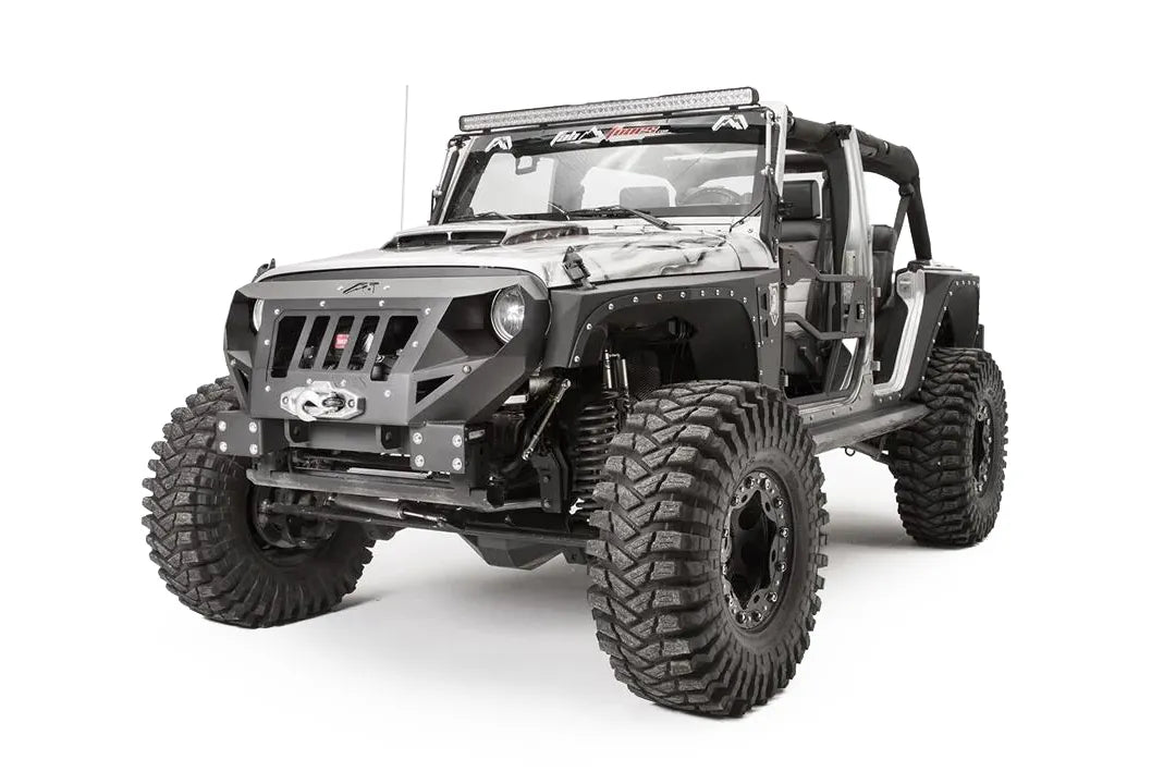 Fab Fours Grumper front bumper in Stubby configuration on a gray Jeep Wrangler JK, front driver-side three-quarter view, showing grille-integrated design, winch housing, round headlight openings