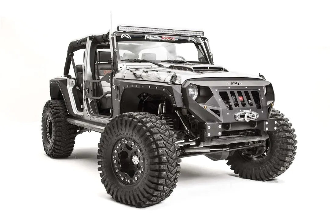 Fab Fours Grumper front bumper in Stubby configuration on a gray Jeep Wrangler JK, straight-on front view, showing grille-integrated design, winch housing, round headlight openings