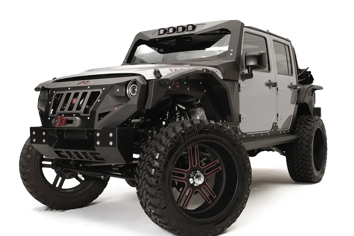 Fab Fours Grumper crash bar with slotted grille on a lifted gray Jeep Wrangler JK Unlimited, driver-side front three-quarter view, with winch and Fab Fours fender flares