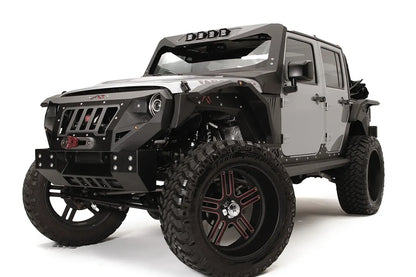 Fab Fours Grumper crash bar with slotted grille on a lifted gray Jeep Wrangler JK Unlimited, driver-side front three-quarter view, with winch and Fab Fours fender flares
