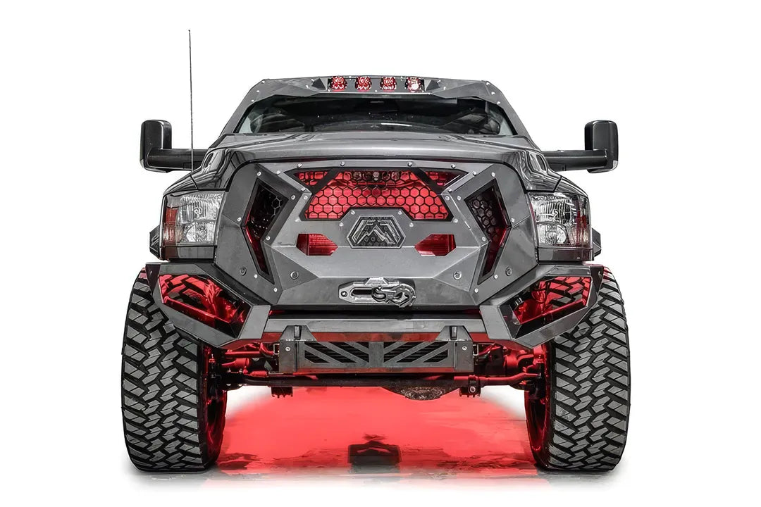 Fab Fours Grumper front bumper on a lifted gray Ram 2500, front view, with red accent lighting behind the honeycomb mesh grille and Warn winch fairlead