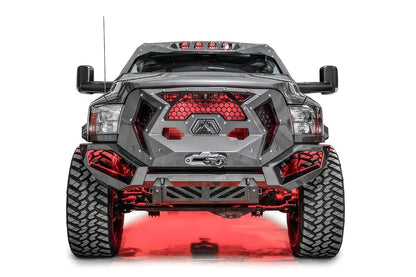 Fab Fours Grumper front bumper on a lifted gray Ram 2500, front view, with red accent lighting behind the honeycomb mesh grille and Warn winch fairlead