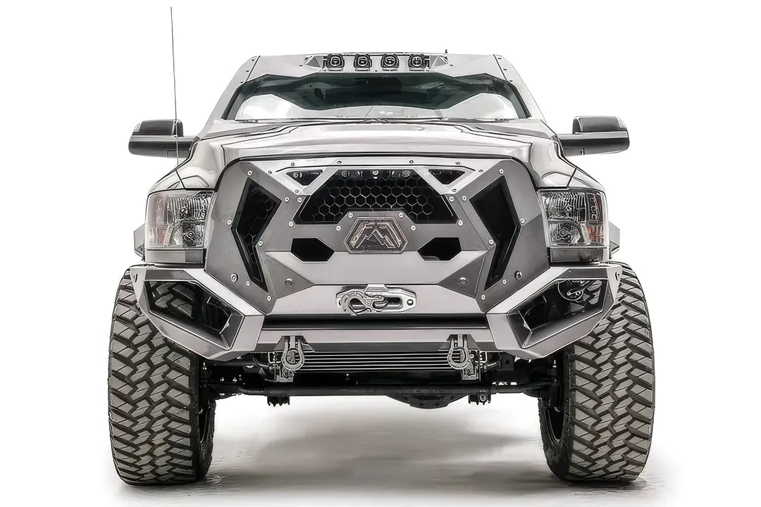 Fab Fours Grumper front bumper on a lifted silver Ram 2500, front view, with honeycomb mesh grille, Fab Fours logo plate, winch fairlead, and D-ring shackles