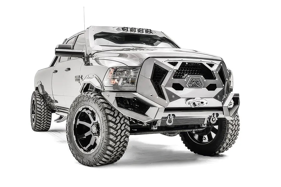 Fab Fours Grumper front bumper with honeycomb mesh grille on a lifted silver Ram 2500, passenger-side front three-quarter view, with winch and D-ring shackles