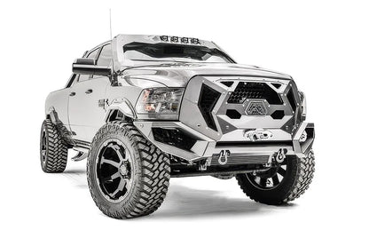 Fab Fours Grumper front bumper with honeycomb mesh grille on a lifted silver Ram 2500, passenger-side front three-quarter view, with winch and D-ring shackles