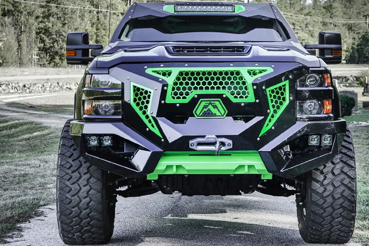Fab Fours Grumper front bumper with green honeycomb mesh grille and green skid plate on a lifted black Chevrolet Silverado 2500HD, front view outdoors