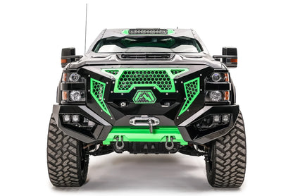 Fab Fours Grumper front bumper on a lifted black Chevrolet Silverado 2500HD, front view, with green honeycomb mesh grille, winch, dual cube lights, D-ring shackles, and green skid plate