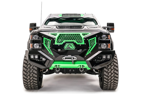 Fab Fours Grumper front bumper on a lifted black Chevrolet Silverado 2500HD, front view, with green honeycomb mesh grille, winch, dual cube lights, D-ring shackles, and green skid plate