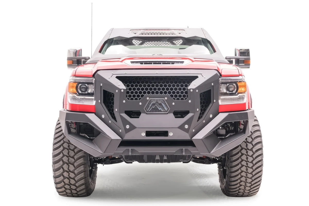 Fab Fours Grumper front bumper on a lifted red GMC Sierra 3500HD, front view, with honeycomb mesh grille, Fab Fours logo plate, and winch opening
