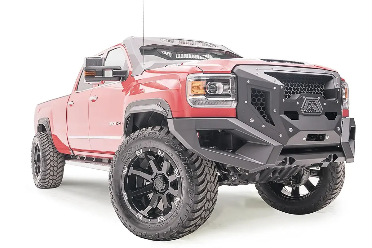 Fab Fours Grumper front bumper with honeycomb mesh grille on a lifted red GMC Sierra 3500HD, passenger-side front three-quarter view, with Fab Fours fender flares